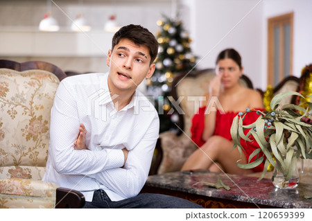 Disappointed young couple arguing among themselves before Christmas Eve while sitting on sofa in living room at home 120659399
