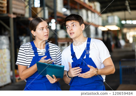 Young woman and young guy warehouse workers checking documents 120659484