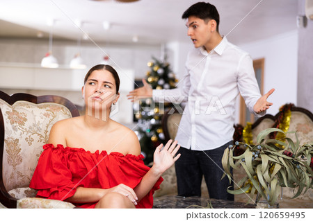 Disappointed young couple arguing among themselves before Christmas Eve while sitting on sofa in living room at home 120659495
