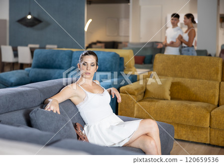 Adult happy smiling female touching sofa in the furniture store before buying 120659536