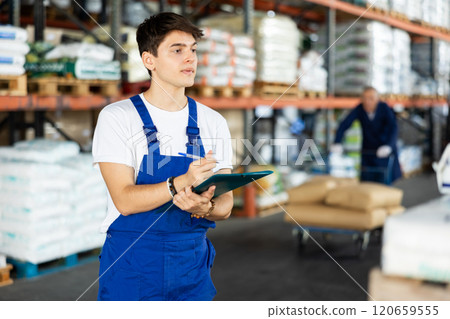 In warehouse of store, guy checks quantity of goods and receipt documents for products 120659555