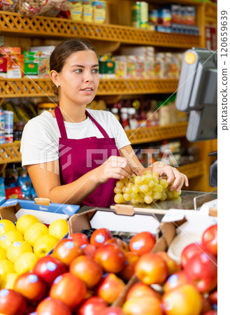 Female shopping assistant weighing grapes in grocery shop Female shopping assistant weighing grapes in grocery shop 120659639