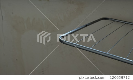 A closeup view of a sleek metal drying rack beautifully set against a simple, plain, unadorned wall surface 120659712