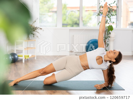 Experienced girl fitness club teacher performs side plank, vasishthasana Experienced girl fitness club teacher performs side plank, vasishthasana 120659717