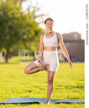 Young woman practicing Vrksasana yoga asana in green park 120659761