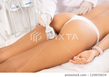 Aesthetician administering ice hammer therapy to tighten skin on female buttocks Aesthetician administering ice hammer therapy to tighten skin on female buttocks 120659834