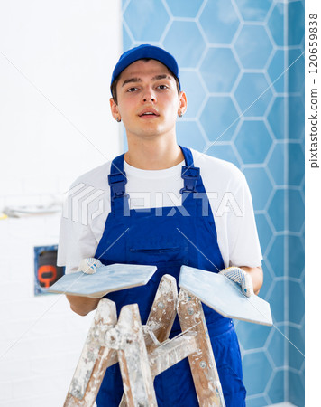 Young tiler working with ceramic tiles for interior decoration of repairable room 120659838