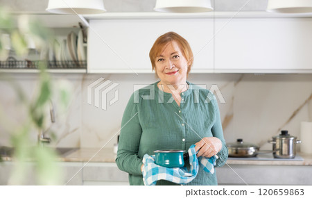 Positive mature woman with a saucepan in her hands 120659863