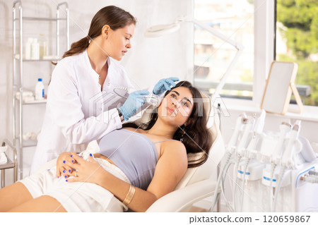 Aesthetician administering hardware facial procedure with ice hammer on young woman 120659867