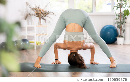 Experienced girl fitness club teacher performs prasarita padottanasana Experienced girl fitness club teacher performs prasarita padottanasana 120659876