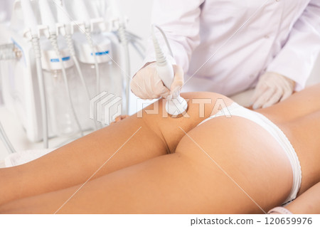 Woman undergoing high-frequency ultrasound procedure on buttocks in cosmetic clinic Woman undergoing high-frequency ultrasound procedure on buttocks in cosmetic clinic 120659976