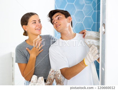 Young couple laying ceramic tiles on walls during home renovation Young couple laying ceramic tiles on walls during home renovation 120660012