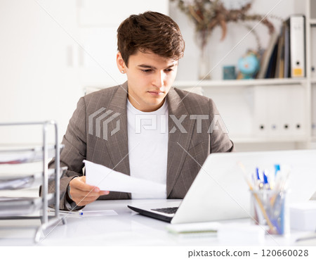 Businessman works in the office - puts documents in order and draws up contract 120660028