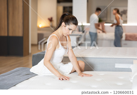 Adult woman chooses mattress in store 120660031