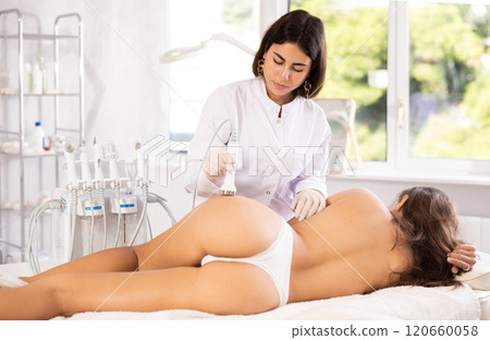 Female doctor making butt beauty massage with vibration attachement 120660058