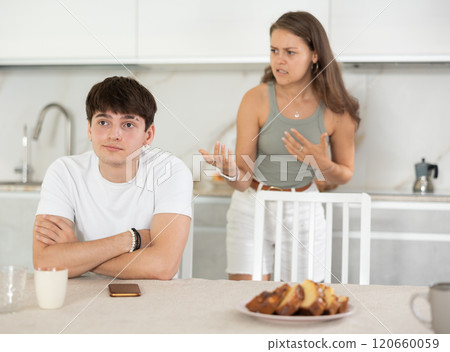 Young woman quarrels with young guy in kitchen Young woman quarrels with young guy in kitchen 120660059