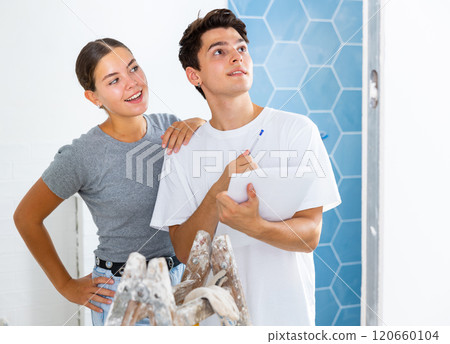 Young couple with documents checks the number of tiles, making important notes Young couple with documents checks the number of tiles, making important notes 120660104