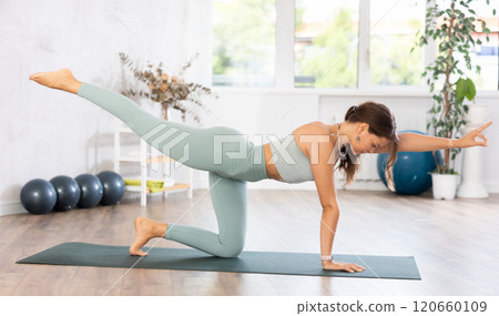 Young woman yoga trainer performing table pose on black rug 120660109