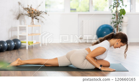 Experienced girl fitness club teacher performs pigeon asana, eka pada rajakapotasana Experienced girl fitness club teacher performs pigeon asana, eka pada rajakapotasana 120660165