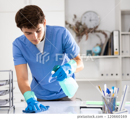 Portrait of worker of office cleaning service wiping furniture with rag and detergent 120660169