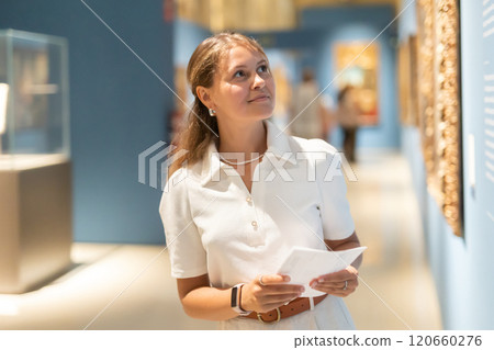 Woman with sheet piece of paper in hands view pictures and icons in museum hall 120660276