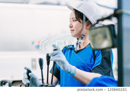 A woman in a helmet driving a forklift 120660281