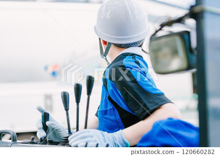 A woman in a helmet driving a forklift A woman in a helmet driving a forklift 120660282