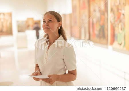 Portrait of young attractive woman holding an information booklet during a visit to fine arts museum 120660287