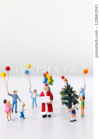 Miniature Santa Claus holding a gift surrounded by children and colorful balloons 120661043