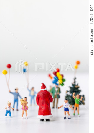Miniature Santa Claus holding a gift surrounded by children and colorful balloons 120661044