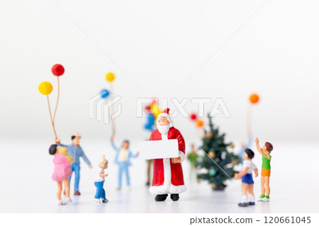 Miniature Santa Claus holding a gift surrounded by children and colorful balloons 120661045