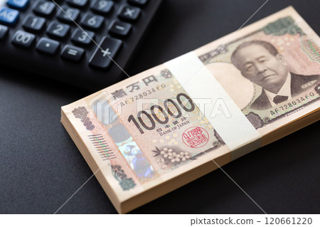 一疊新的 10,000 日元鈔票和黑色背景上放置的黑色計算器 120661220