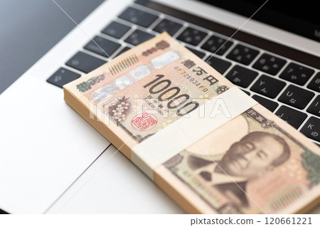 A stack of new 10,000 yen bills and a computer placed on a black background A stack of new 10,000 yen bills and a computer placed on a black background 120661221