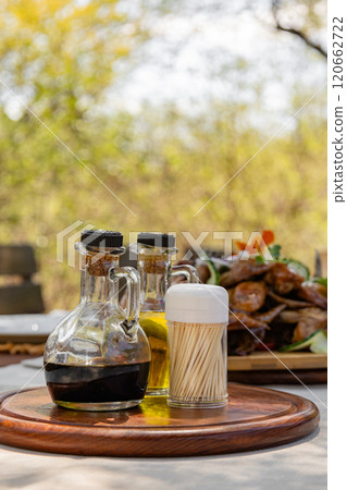 Two sauces in glass decanters and a jar of toothpicks on a wooden tray Two sauces in glass decanters and a jar of toothpicks on a wooden tray 120662722