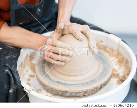 Close-up of a potter's hands working on a pottery wheel. Close-up of a potter's hands working on a pottery wheel. 120664210