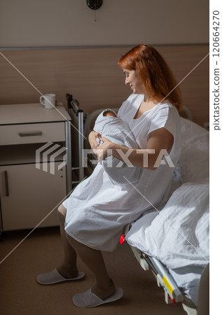 Caucasian woman holding newborn son while sitting on couch in maternity hospital ward. Caucasian woman holding newborn son while sitting on couch in maternity hospital ward. 120664270