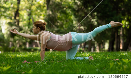 Pregnant caucasian woman doing yoga in the park.  120664337