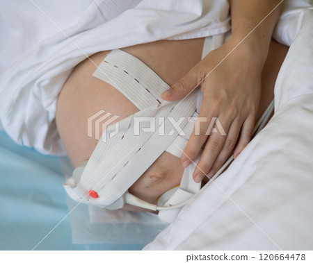 Close-up of pregnant woman's belly with Cardiotocography sensor in delivery room of maternity home. Close-up of pregnant woman's belly with Cardiotocography sensor in delivery room of maternity home. 120664478