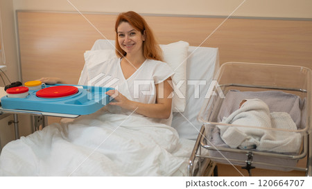 Caucasian woman eats on hospital bed after giving birth. Caucasian woman eats on hospital bed after giving birth. 120664707