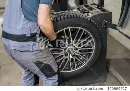 Mechanic balancing a wheel in a workshop.  120664717