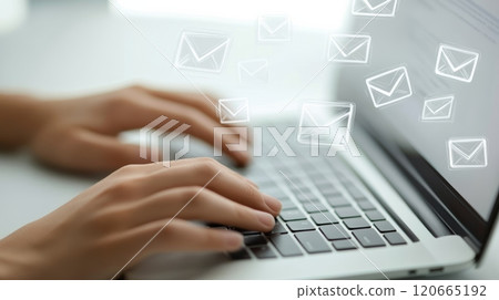 Hands typing on laptop keyboard with email icons appearing on the screen, suggesting communication, marketing, and social media activity in a modern office setting 120665192