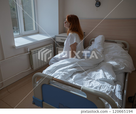 An unhappy pregnant woman sits on a couch in a hospital room. An unhappy pregnant woman sits on a couch in a hospital room. 120665194