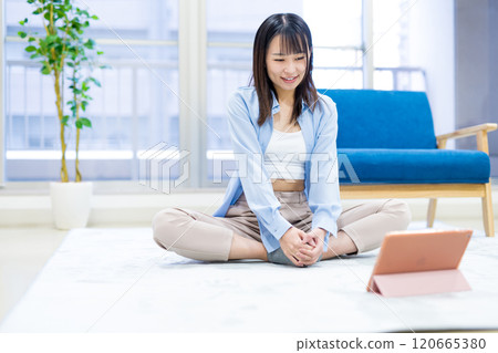 Young woman exercising at home while watching YouTube videos on tablet Yoga Stretching Diet Health Young woman exercising at home while watching YouTube videos on tablet Yoga Stretching Diet Health 120665380
