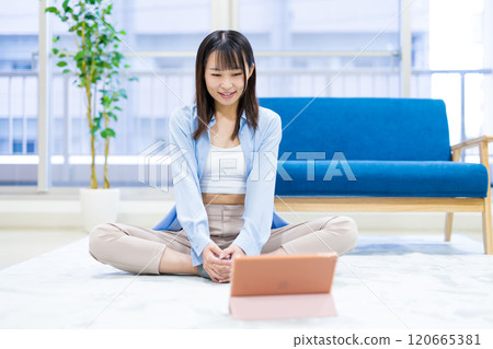 Young woman exercising at home while watching YouTube videos on tablet Yoga Stretching Diet Health 120665381