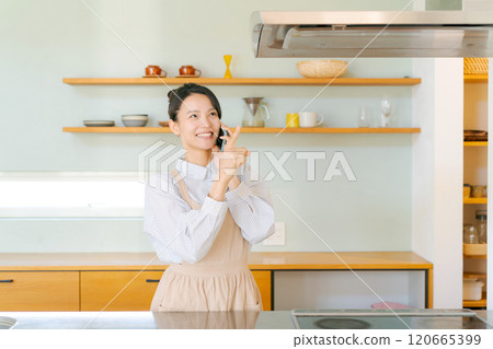 Woman talking on smartphone in kitchen 120665399