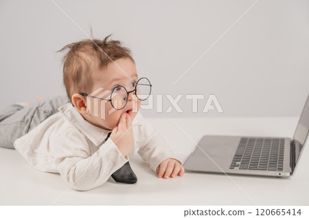 Cute baby in glasses and suit working on laptop. Cute baby in glasses and suit working on laptop. 120665414