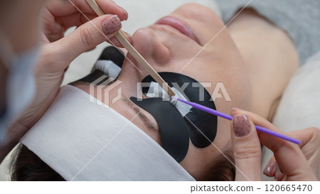 The master cleans the client's eyelashes from sebum before extensions. The master cleans the client's eyelashes from sebum before extensions. 120665470