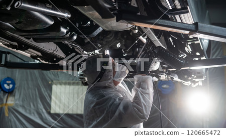 The master sprays an anti-corrosion compound on the bottom of the car.  120665472