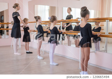 Caucasian woman teaches little girls ballet at the barre. Caucasian woman teaches little girls ballet at the barre. 120665494