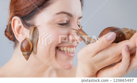 Closeup of a Caucasian woman holding a large snail. The use of shellfish in cosmetology. Closeup of a Caucasian woman holding a large snail. The use of shellfish in cosmetology. 120665497